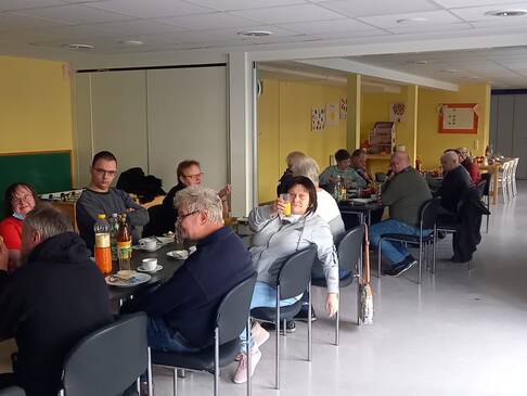 Viele Menschen sitzen an einem langen, gedeckten Tisch.