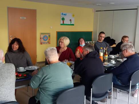 Viele Menschen sitzen an einem langen, gedeckten Tisch.