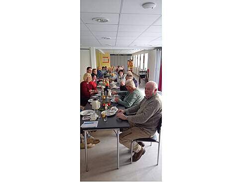 Viele Menschen sitzen an einem langen, gedeckten Tisch.