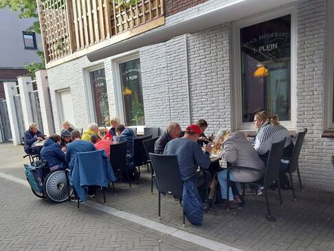 Viele Personen essen an Tischen Pommes.