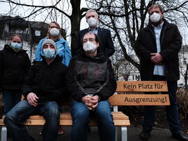 Menschen auf und hinter der Bank mit dem Bürgermeister.