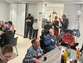 Viele Personen sitzen an Tischen in einem Raum.