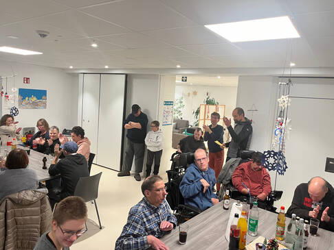 Viele Personen sitzen an Tischen in einem Raum.