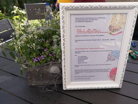 Dankesschreiben in Bilderrahmen, daneben steht eine Pflanze.