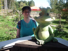 Frau neben Froschskulptur.
