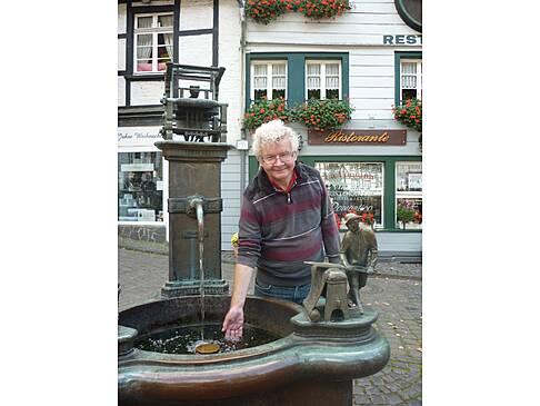 Ein Mann streckt seine Hand in das Wasser eines Brunnens.