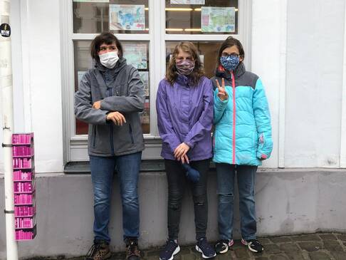 Drei Mädchen vor einem Fenster. Sie haben Masken an.