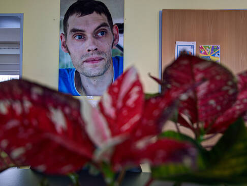 Ein Bild mit Mann im Hintergrund, vorne eine rot, weiße Blume.