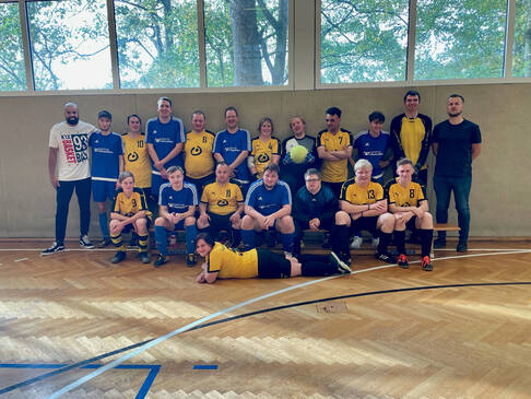 Gruppenbild einer Fussballmannschaft in einer Sporthalle.
