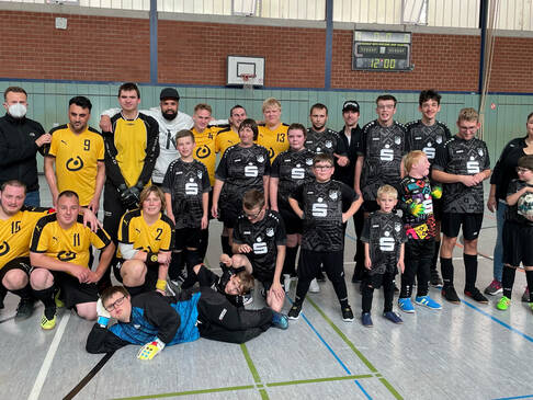 Zwei Fussballmannschaften in einer Halle im Trikot.