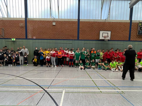 Einige Fussballmannschaften in einer Sporthalle.