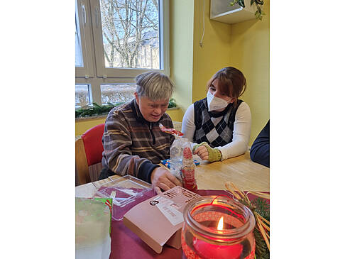 Eine Frau schaut sich ihre Geschenke an und eine andere sitzt neben ihr.