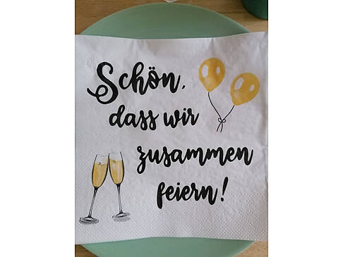 Eine Serviette mit der Schrift Schön, dass wir feiern.