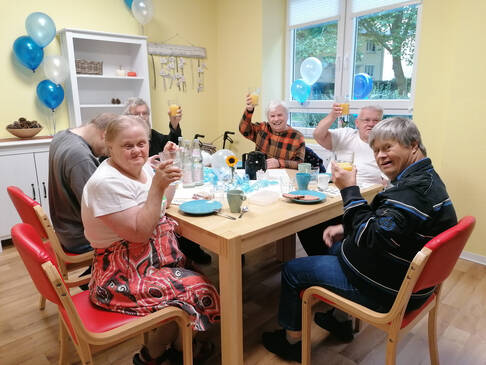 Mehrere Personen sitzen am Tisch und schauen.
