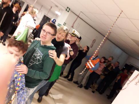 Mehrere Menschen stehen hintereinander und fassen sich an die Schultern.