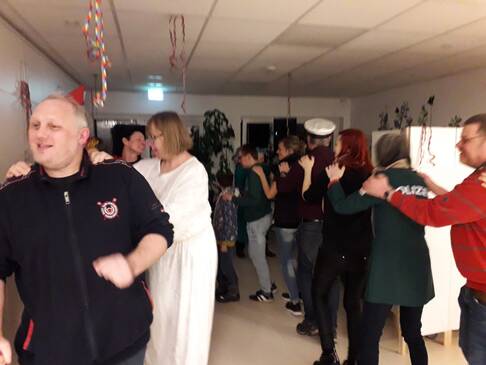 Mehrere Menschen stehen hintereinander und fassen sich an die Schultern.