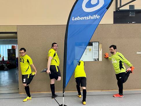 Sportler wäremen sich auf und stützen sich an einer Wand.
