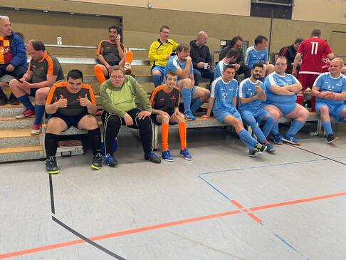 Sportler die am Spielfeldrand sitzen.
