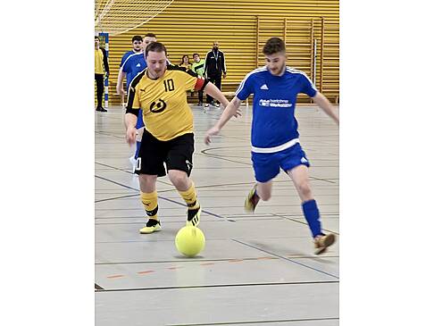 Zwei Fussballer laufen hinter einem Ball her.