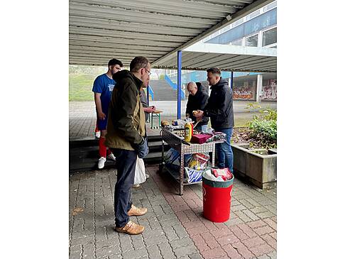 Zwei Personen grillen, zwei Personen stehen vorm Grill.