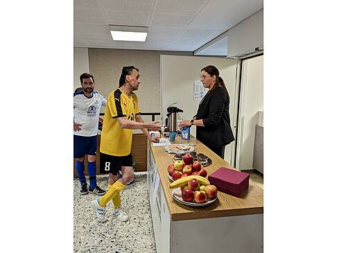 Einn Fussballer unterhält sich mit einer Frau an der Kuchentheke.