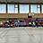 Mehrere Fussballteams sitzen in der Halle am Rand.