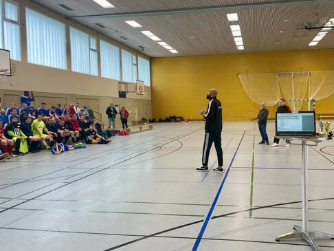 Ein Mann spricht zu den Fussballern in der Halle.