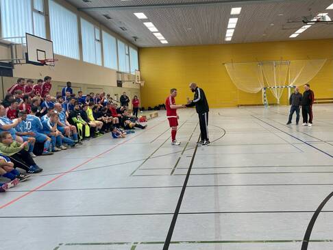 Ein Fussballer erhält einen Pokal von einem Mann.