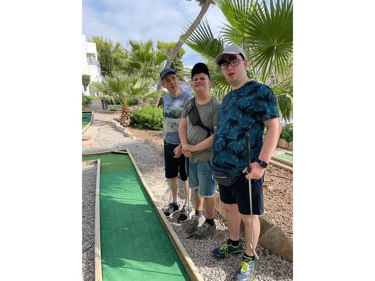 Drei Gäste an einer Minigolfbahn.