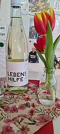 Lebenshilfe Sekt neben einer Tulpe auf einem Tisch.