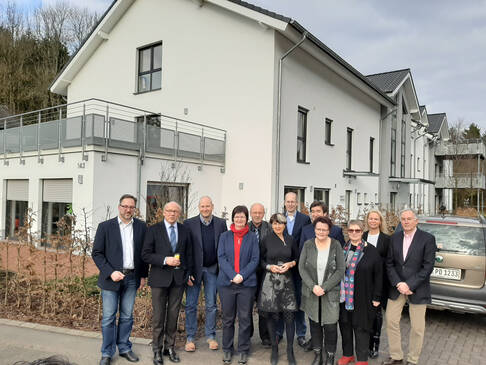 Zwölf Männer und Frauen stehen draussen nebeneinander.