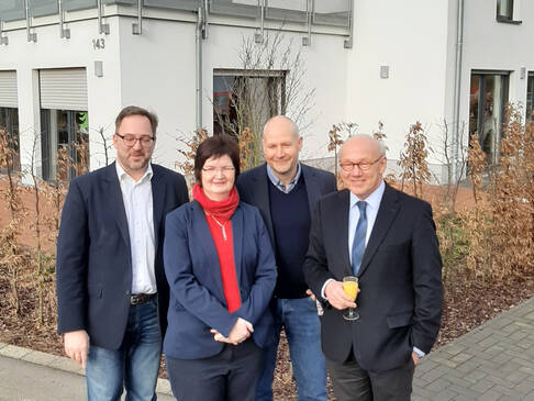 Drei Männer und eine Frau lächeln.