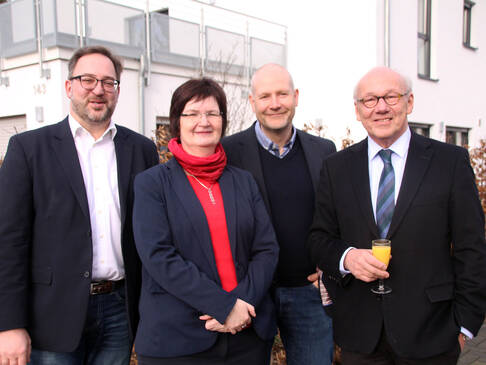 Drei Männer und eine Frau lächelt.
