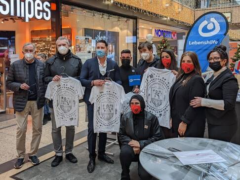 Menschen mit bedruckten Shirts in der Hand.