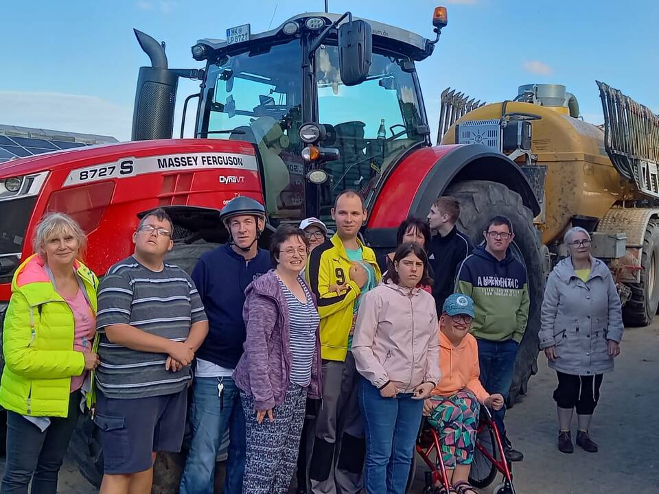 Gruppenbild vor einem großen, roten Trecker.