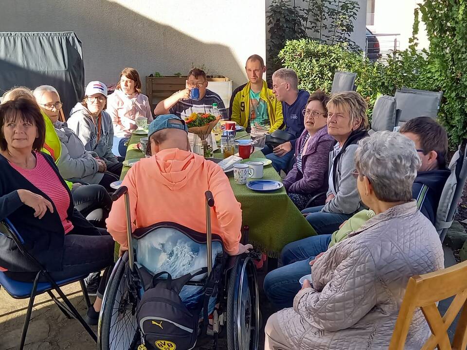 Viele Personen an einem gedeckten Kaffeetisch.