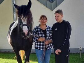 Zwei Personen neben einem Pferd.