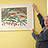 Ein Mann hält ein Bild an der Wand.
