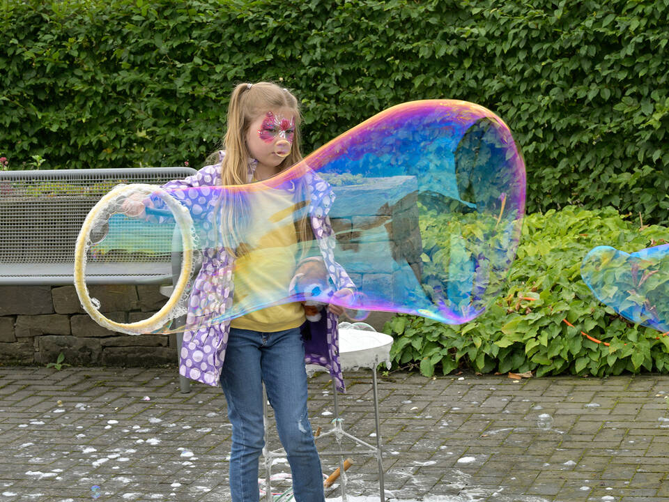 Ein Mädchen macht eine riesen Seifenblase.