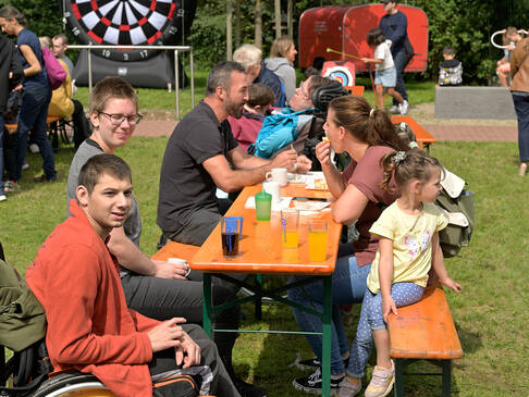 Personen sitzen an einem Tisch auf einer Wiese.