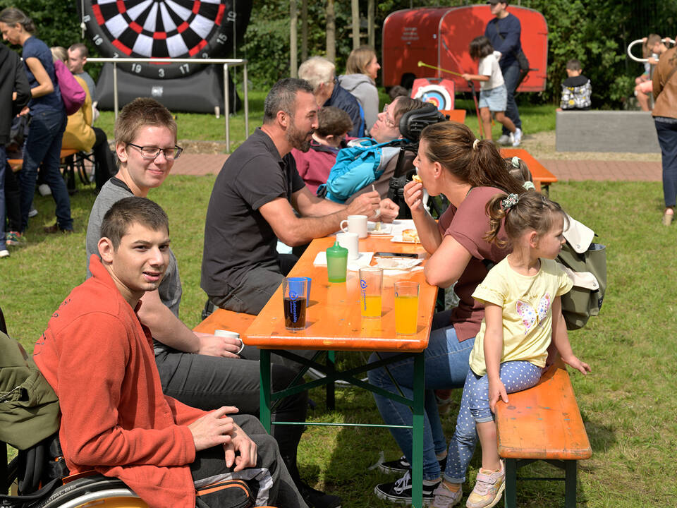 Personen sitzen an einem Tisch auf einer Wiese.