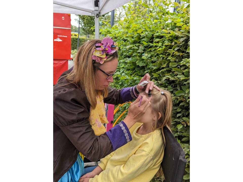 Eine Frau schminkt ein Kind.