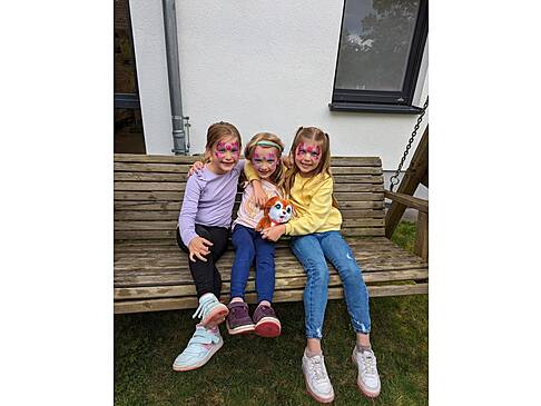 Kinder sitzen auf einer Holzbank.