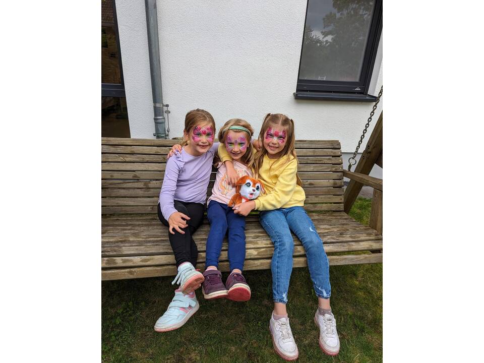 Kinder sitzen auf einer Holzbank.