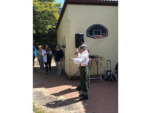 Zwei Männer in Trachten scheinen in der Sonne zu singen.