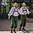 Zwei Männer in Tracht stehen in der Sonne und einer hält sich ein Mikrofon vor den Mund.
