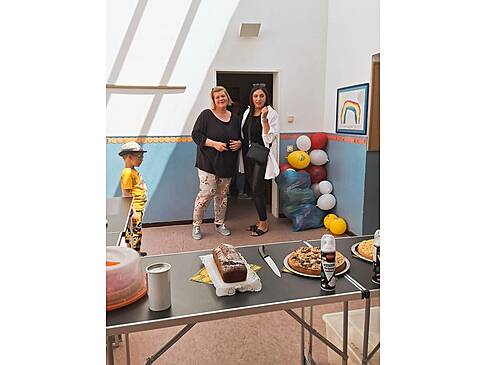 Zwei Frauen in einem Raum, vorn im Bild steht Kuchen.