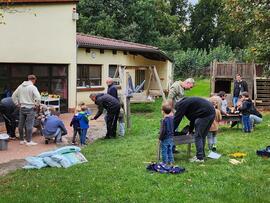 Viele Männer bauen Hochbeete mit Kindern auf.