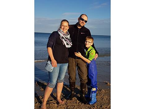 Eine Frau, ein Mann und ein Junge stehen am Strand.