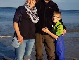 Eine Frau, ein Mann und ein Junge stehen am Strand.